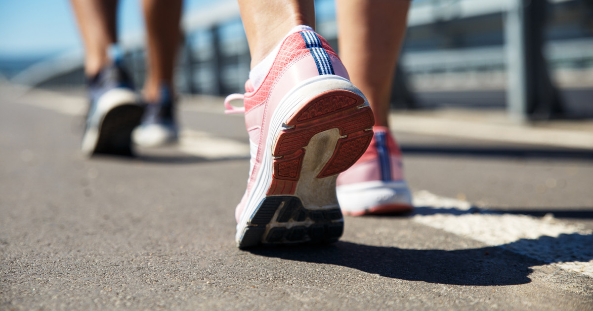 A person tying their walking shoes at the front door, with a small smile, ready to head out for a walk.