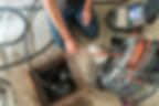 A man repairs a sewer using a tool, focused on fixing the underground pipe system