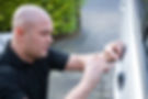 A professional locksmith repairing a lock of a silver car