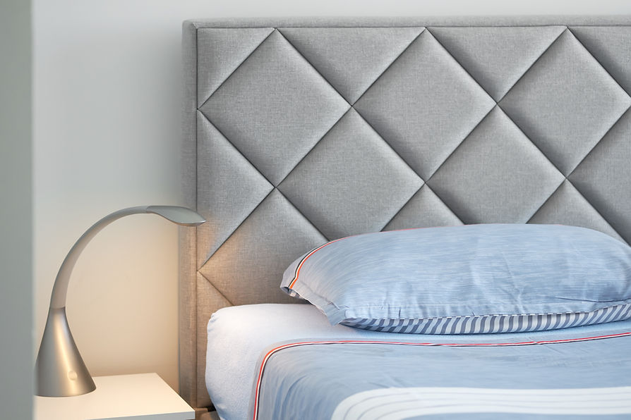 A grey upholstered headboard with a diamond pattern