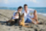 happy young family in white clothing have fun and play with beautiful dog at vacations on