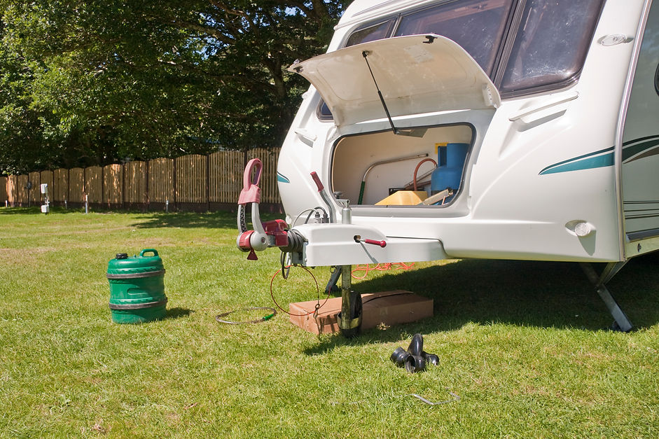 White touring caravan with open front locker parked on campsite grass hitching area