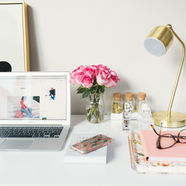 A work from home set up with laptop, notepad, glasses and flowers