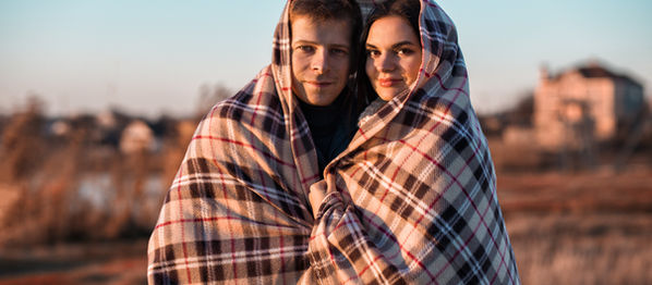 Couple wrapped together in a blanket, holding each other closely with warmth and connection, symbolizing emotional safety, healing relationship patterns, intimacy, and moving beyond survival mode in love.