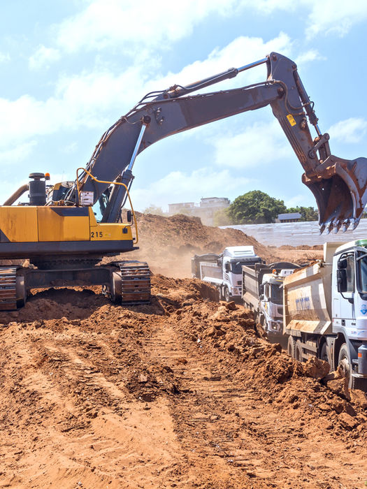 Excavator loading a dump truck at a construction site.