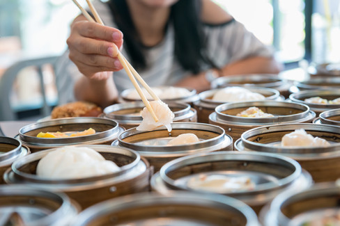 A hand extends into a dim sum container.