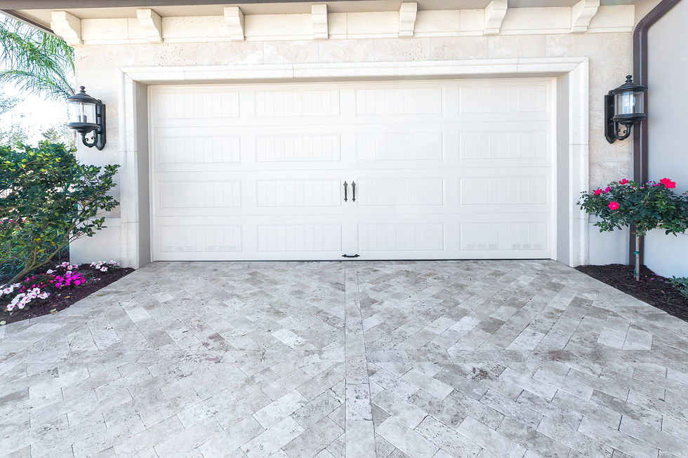 Classic white paneled garage door with a light gray stone paver driveway