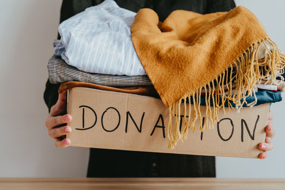 Person holding a donation box filled with clothing