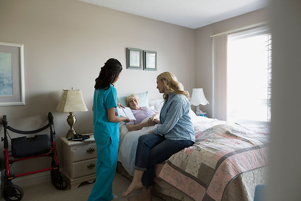 Home caregiver talking to senior woman and daughter in bedroom