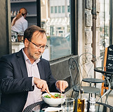 Üzletember egy kávézóban reggelizik