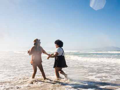 two friends dancing in the ocean having fun