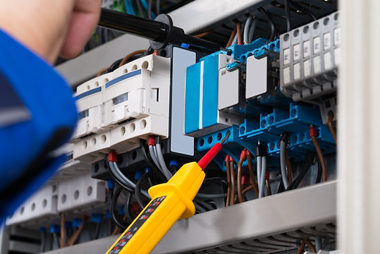 Male Electrician Examining Fusebox With Voltage Tester