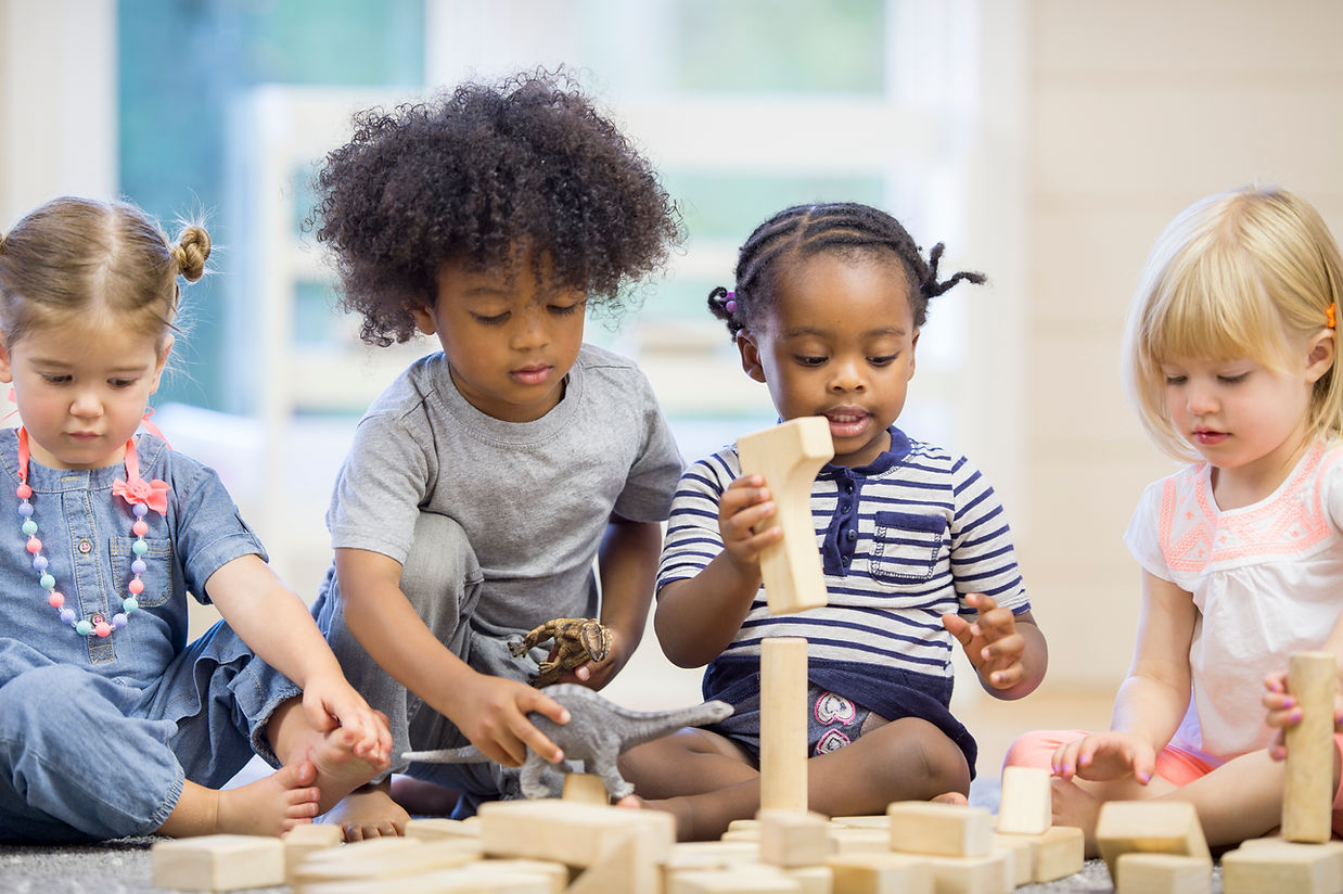 A multi-ethnic group of toddlers are sitting together on the floor holding playing