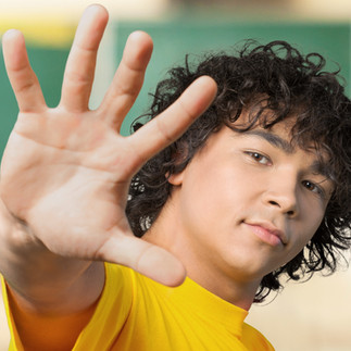 teenage boy giving a high five with a confident look on his face 