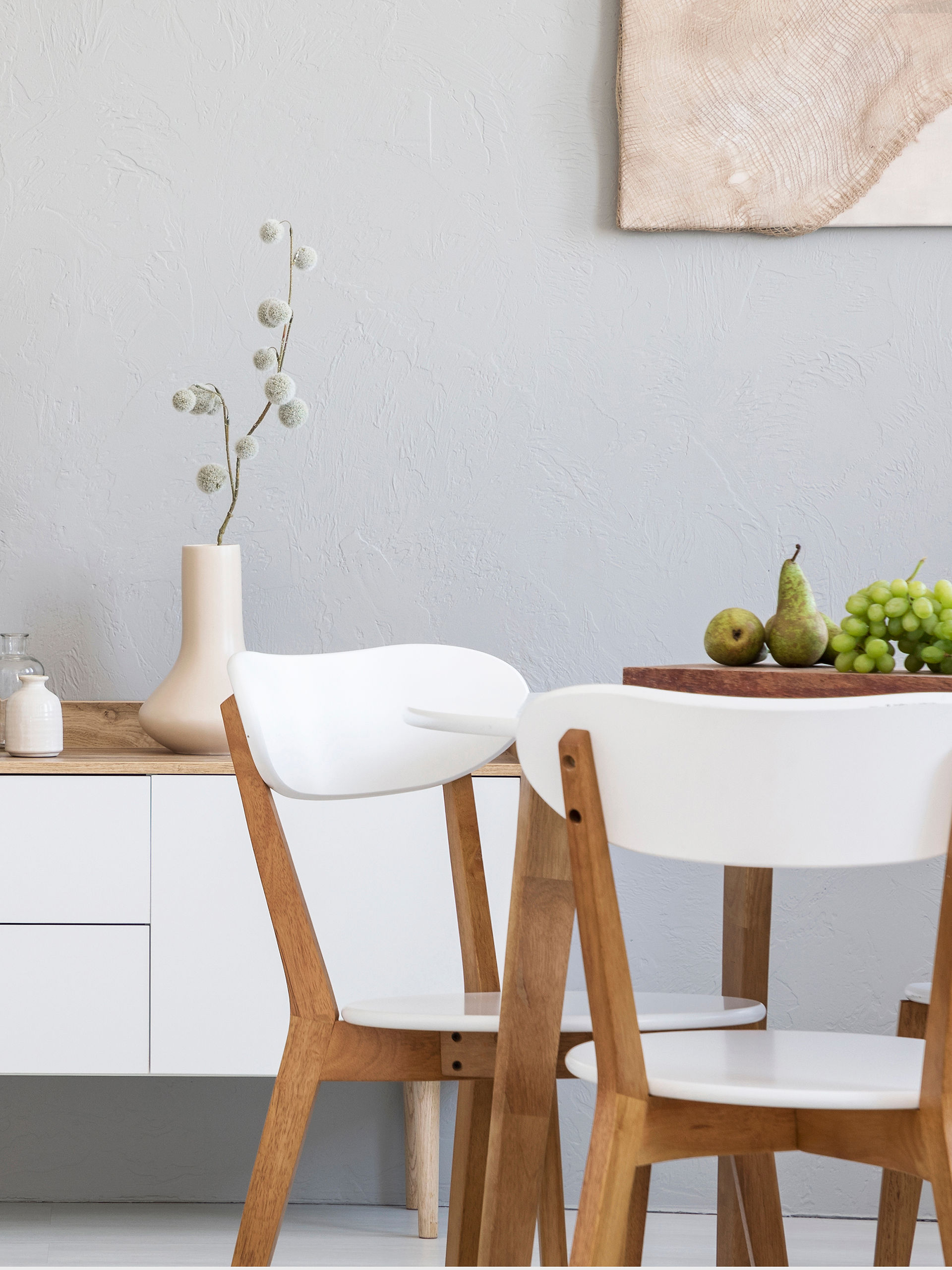Decorating a dining room with a cupboard and two white wooden chairs, creating a friendly atmosphere and an elegant, simple space.