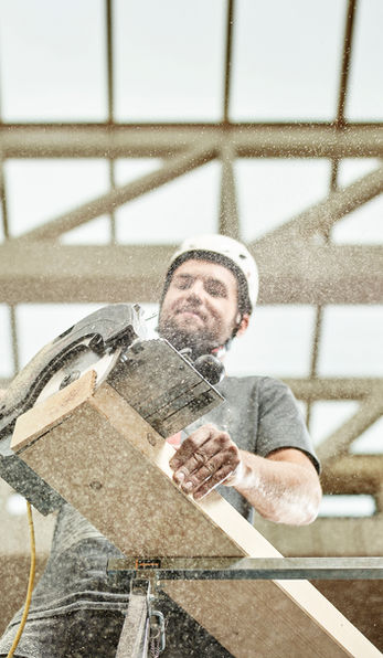 Ein Handwerker sägt einen Holzbalken zurecht 