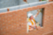 Construction worker laying bricks and using measuring tape