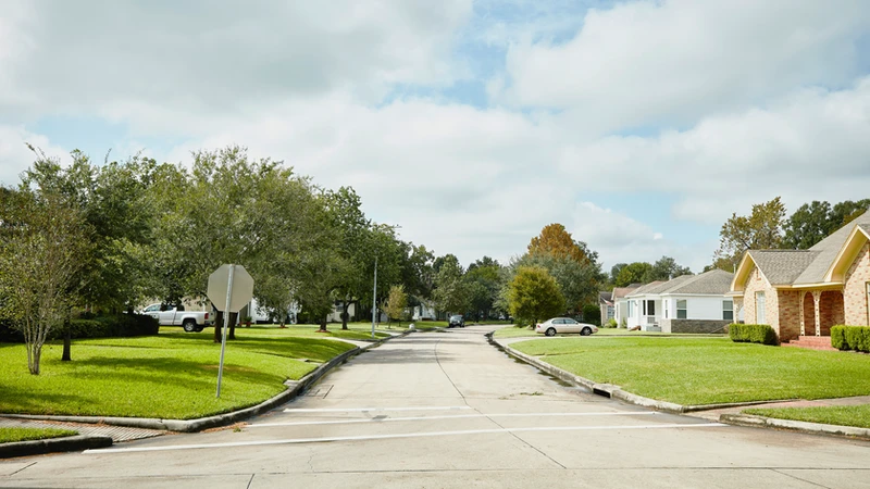 a white car is parked on the side of the road in a residential neighborhood