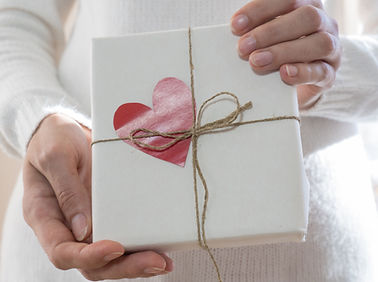 A gift wrapped in a simple homemade white wrapping tied with a thin jute and a heart paper decor.