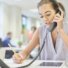 a young woman in a casual modern office chats to a client on the phone