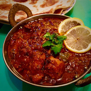 A delicious red meat curry garnished with fresh coriander and lemon slices