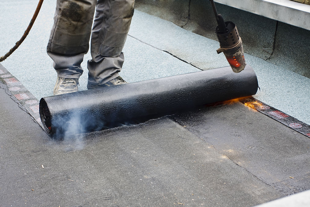 A roofer covering a roof with roofing felt