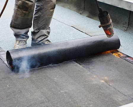 A roofer covering a roof with roofing felt