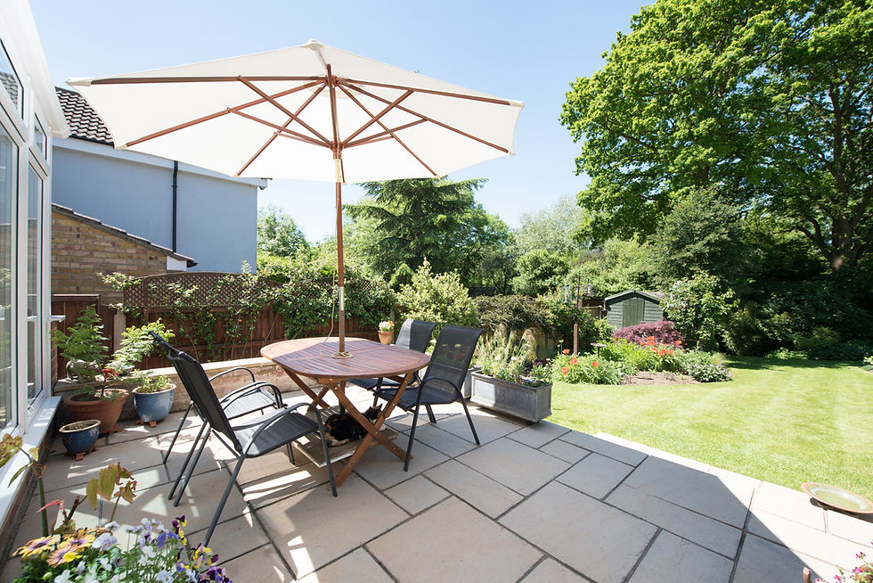 Garden patio set with parasol umbrella, dining table, and chairs overlooking a lawn