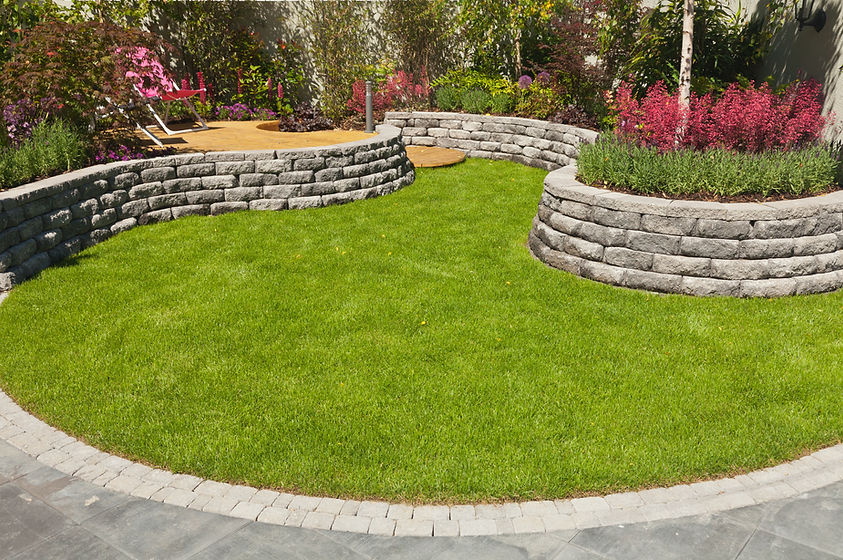 A neatly manicured lawn bordered by curved stone retaining walls with lush green grass