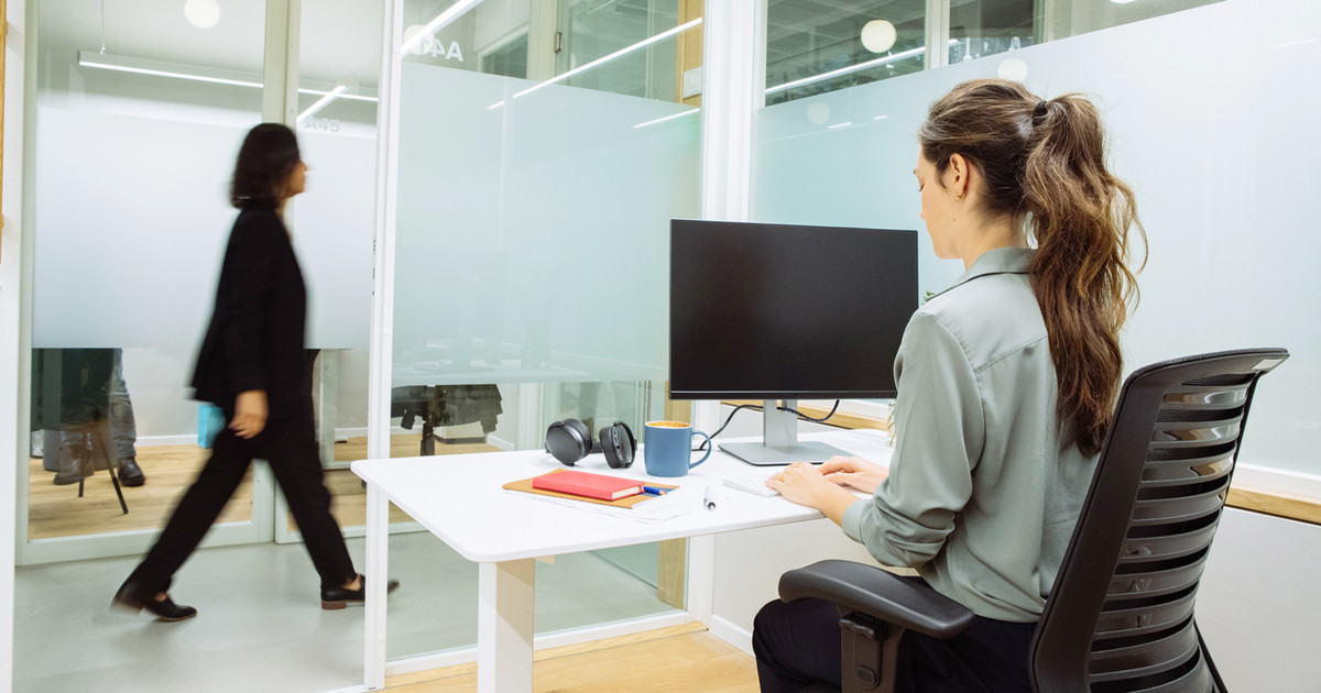 A person comfortably working at a desk with an adjustable chair, monitor at eye level and opportunities to alternate between sitting, standing and moving throughout the day.