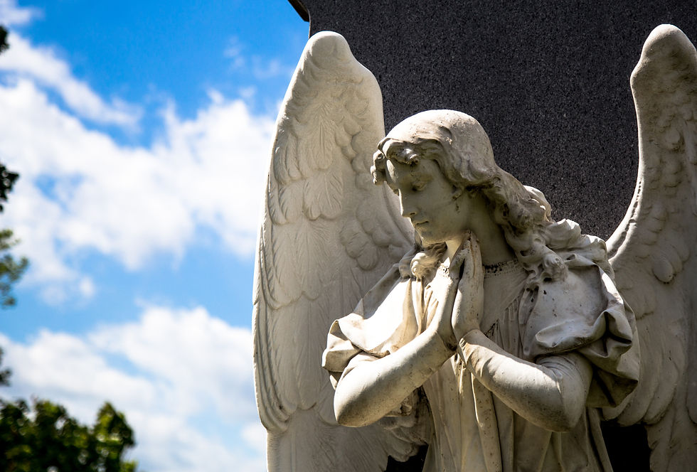 Low Angle View Of Angel Statue In Cemetery Against Cloudy Sky