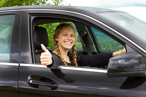 Young woman in car with thumb up