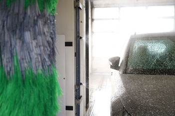Car getting washed by large green brush in an automatic car wash
