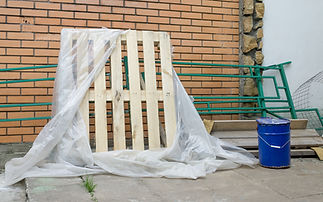 New wooden pallet wrapped in cellophane near brick wall