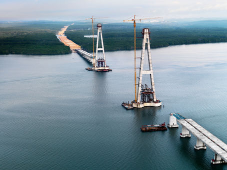 A bridge being constructed across the water with gaps between the supporting towers.