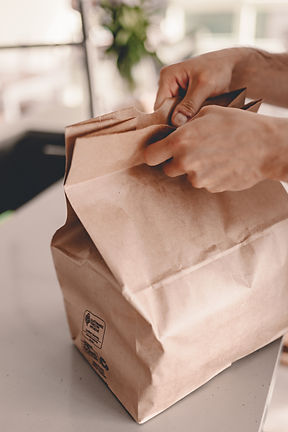 The person holding a folded takeaway bag