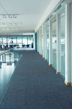 Bright showroom interior featuring glass partitions and dark grey textured flooring