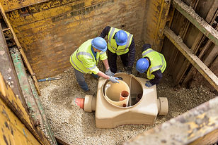 Apprentice builders training with drainage in hole on building site