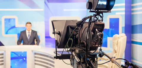 Cámara de televisión en un plató, enfocando a un presentador.