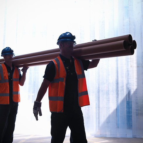 Workers carrying pipes together