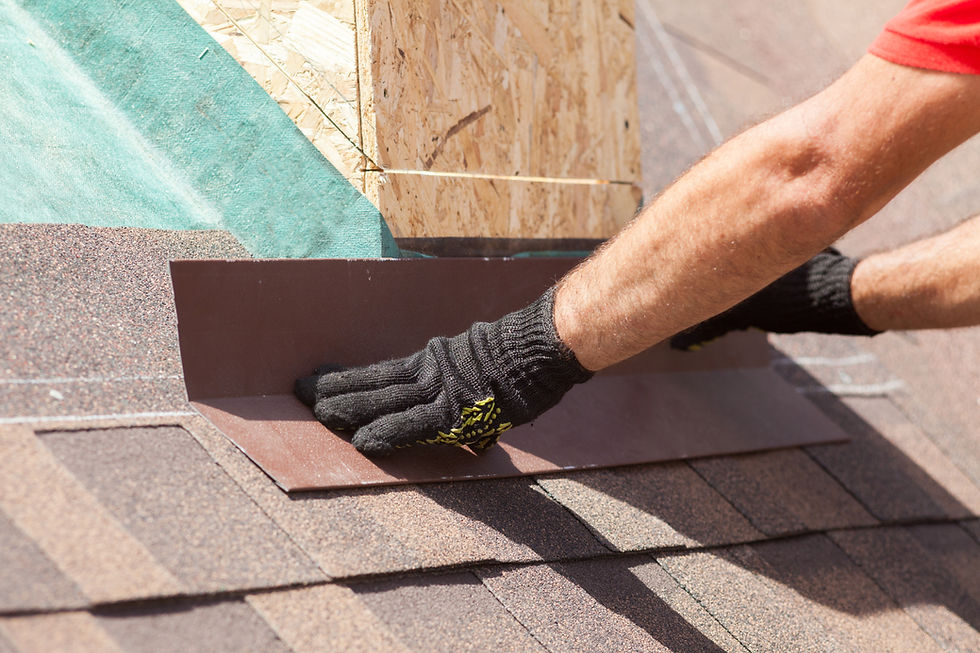 Worker in gloved hands fixing or trimming dark shingles on a roof edge