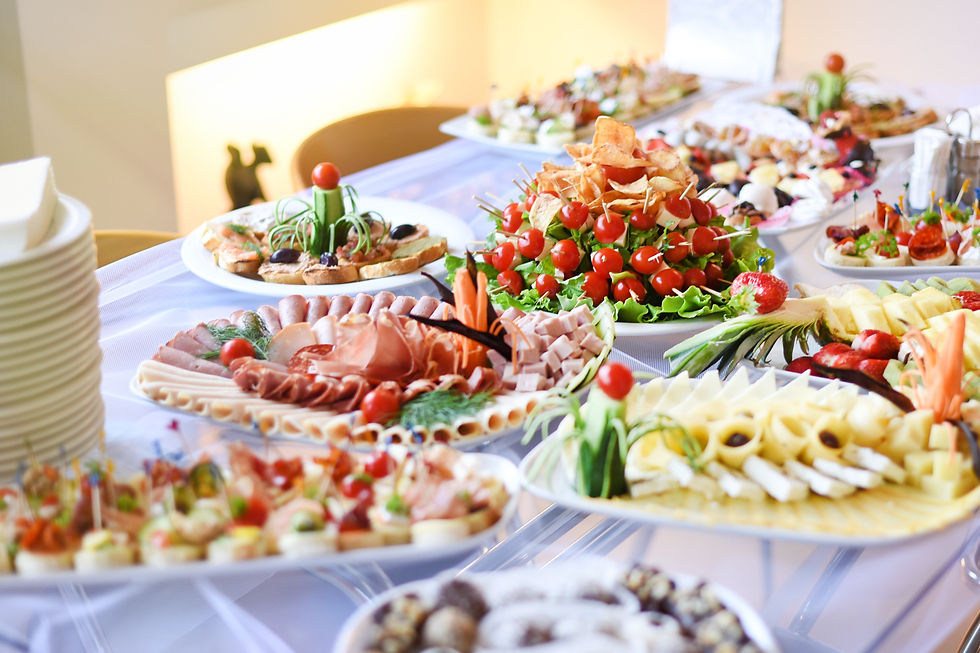 Catering buffet table with platters of cold cuts, cheese, and fresh vegetables