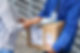 A person signs a clipboard held by a delivery worker in a blue uniform