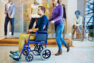 Woman wheeling a disabled young man in shopping mall