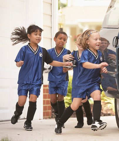 Children in soccer outfits getting into car