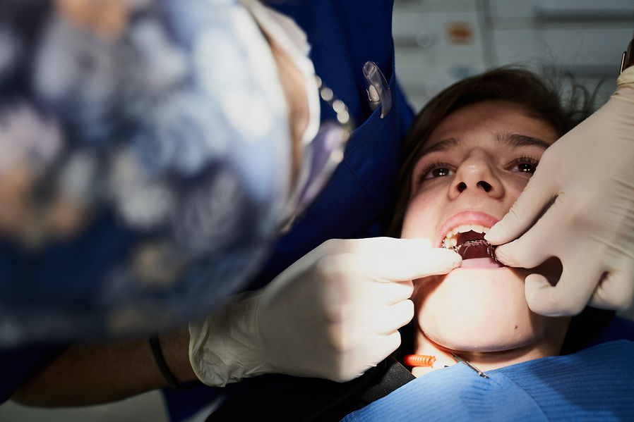 Dentist adjusting a dental appliance inside a patient’s mouth.