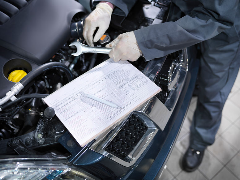 A mechanic holding tools and inspecting a car engine