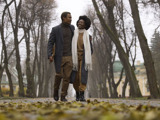 An African American Male-Female presenting couple walk in park