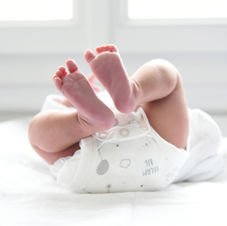 Baby in diaper from below showing infant's feet and legs