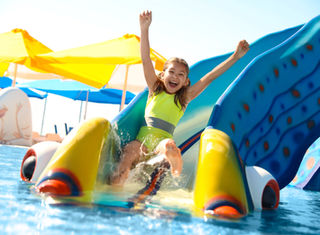 Famille explorant une forêt magique avant de profiter des toboggans et bassins d’un parc aquatique tropical dans le Jura